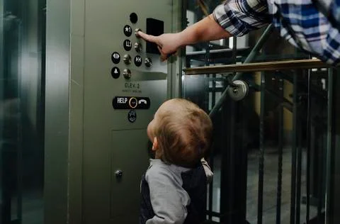 Son looking at mother pressing elevator button Fotos de archivo