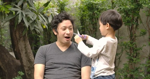 Son playing at be a barber do haircuts to his father. Stock Footage 129055668