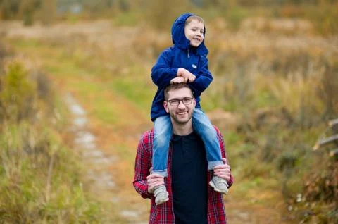 The son sits on his dad s shoulders. Walking in the country Stock Photos