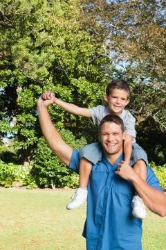Son sitting on his fathers shoulders Stock Photos