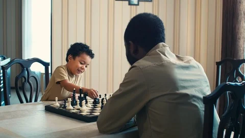 Son studying to play checkmate with father at home Stock Footage 100691688