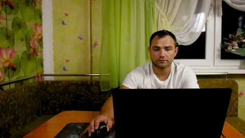 Сoncentrated man, sitting at home at the kitchen table man uses computer, looks Stock Footage 119973659