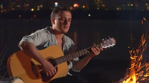 A song with a guitar by the fire Stock Footage 82298713