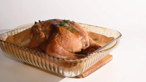 Сooked roasted chicken is being transferred to a wooden serving board. Stockbeeldmateriaal 305649685