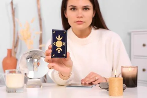 Soothsayer predicting future at table indoors. Focus on tarot card Stock Photos