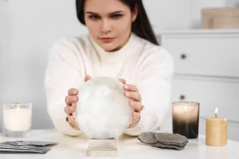 Soothsayer predicting future at table in room, focus on crystal ball Stock Photos