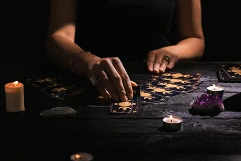 Soothsayer predicting future with tarot cards at table in darkness, closeup Stock Photos