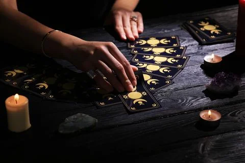 Soothsayer predicting future with tarot cards at table in darkness, closeup Stock Photos