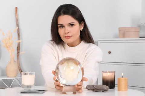 Soothsayer using crystal ball to predict future at table in room 스톡 사진