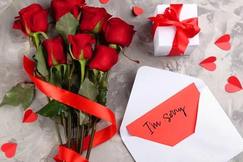 Sorry card in envelope, gift box and red roses on grey table, top view Stock Photos