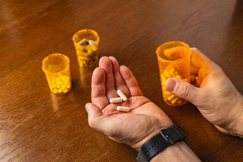 Sorting and examining various pills in bottles on a wooden table Fotos de archivo