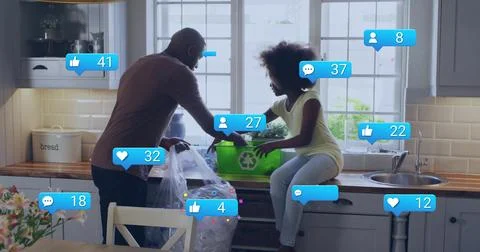 Sorting dad and child loading recyclables on counter in kitchen, with green bin Stock Photos