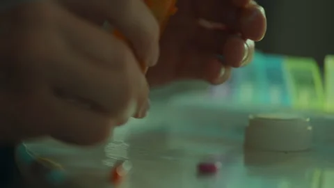 Sorting. A patient in home clothes skillfully takes pills in the kitchen at Stock Footage 257429061