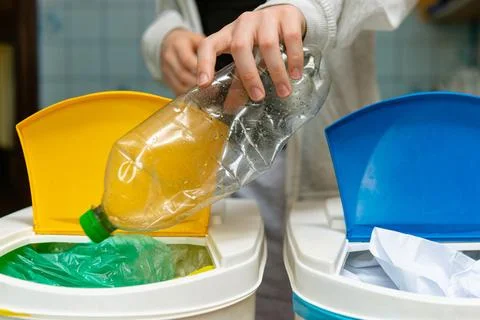 Sorting plastic bottle into a yellow recycling bin Photos
