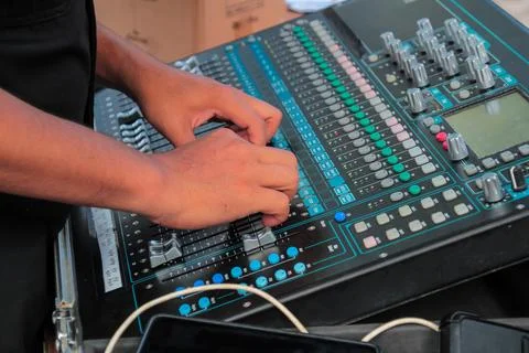 Sound engineer adjusting digital faders on a multi-channel audio mixing board Stock Photos
