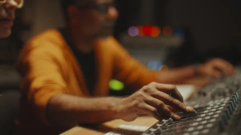 Sound Engineer Adjusting Levels on Mixing Console as Working with Musician Stock Footage 302708543