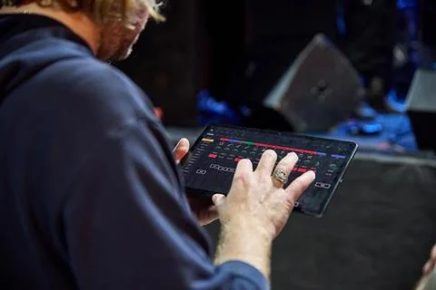 Sound engineer adjusts digital mixer during concert sound check under blue .. 库存照片