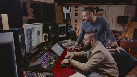 Sound engineer and musicians working in boutique recording studio Stock Footage
