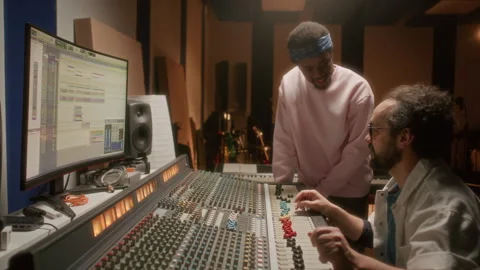 Sound Engineer and Rapper Working on Audio Tracks in Music Recording Studio Stock Footage 334364094