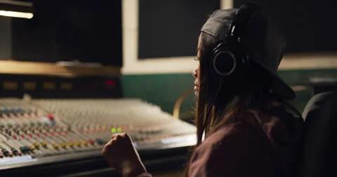 Sound engineer bobs her head to music she is working on at night in recording st Stock Footage 199460663