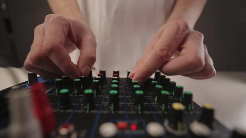 Sound engineer hand adjusting faders and knobs on audio mixing console in studio Stock Footage 323450935
