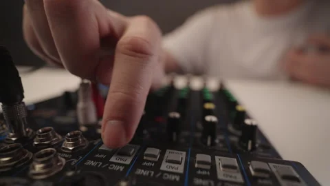Sound engineer hand pressing buttons on audio mixing console, creating dynamic Stock Footage 323451427