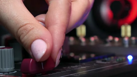 Sound engineer hands adjusting knobs and faders on audio mixer in recording Stock Footage 336249912