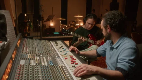 Sound Engineer Mixing Audio while Guitarist Playing Music in Recording Studio 库存影片 334370377