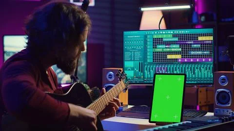 Sound engineer practices playing acoustic guitar using learning app tutorial Fotos de archivo