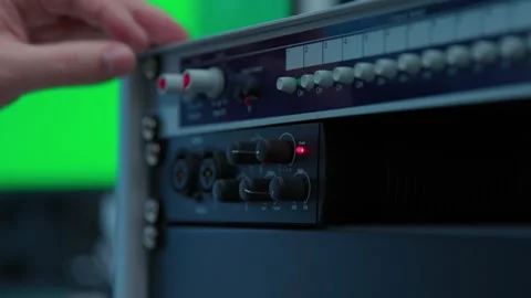 A sound engineer pushing buttons on a mixer to control it Stockbeeldmateriaal 334584426