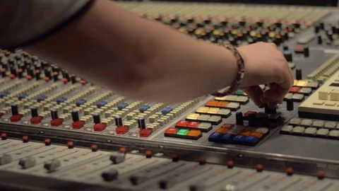 Sound engineer turning the knobs on a Neve mixer in a music studio Stock Footage