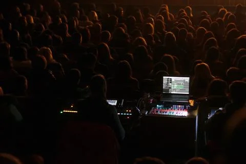 Sound engineer at the work process.A vibrant concert audience in a dimly li.. Stock Photos