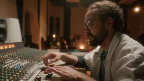Sound Engineer Working at Mixing Desk in Music Production Studio Vidéo 334364407