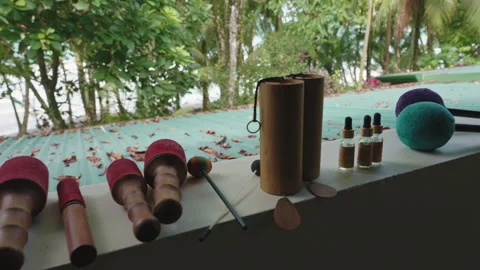 Sound healing instruments and essential oil bottles arranged on a ledge with a 库存影片 336058457