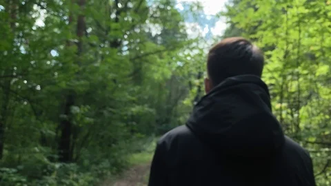 With sound. Man in a black jacket walking  in the woods on a sunny day.  Stock Footage 113094319