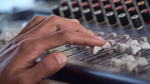 Sound technician adjusting mixer knobs, audio console with LED meters, music Stock Footage 344431876