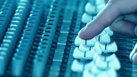 Sound technician hands working on audio mixer faders and knobs Video stock 87319545