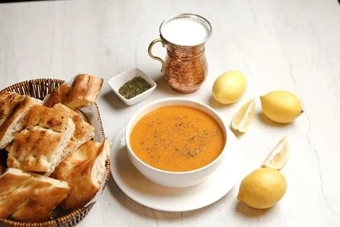 Soup and bread served with lemon and yogurt in a bowl on a table Stock Photos