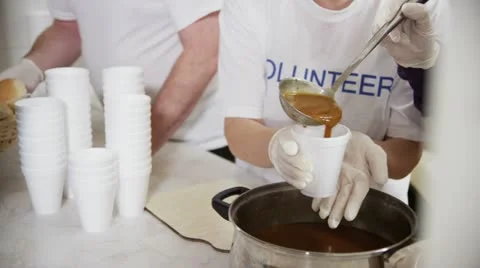 Soup kitchen volunteers help to feed the homeless Stock Footage 20594094