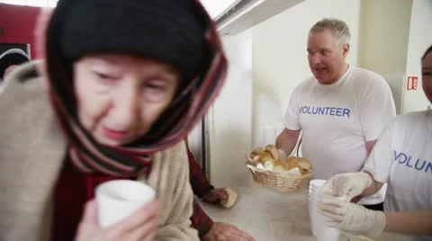 Soup kitchen volunteers help to feed the homeless Stock Footage 20601566