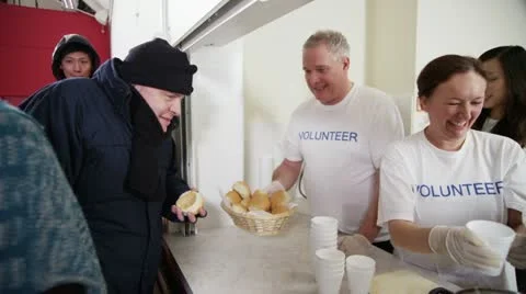 Soup kitchen volunteers help to feed the homeless Stock Footage 20602754