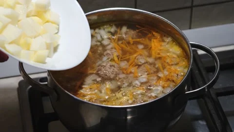 Soup preparation process. Putting potato in bouillon. Close-up. Selective focus Vídeos de archivo 154996742