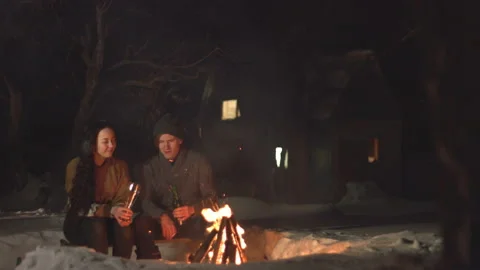 Сouple by the fire with beer. 2 shots. Stockbeeldmateriaal 106459596