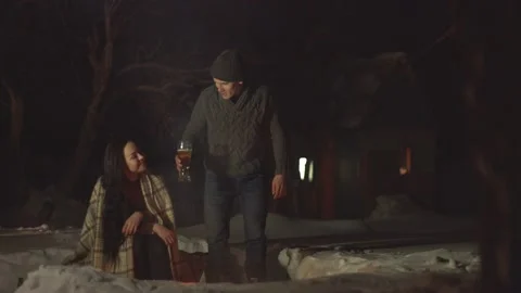 Сouple by the fire with beer. 2 shots. Stockbeeldmateriaal 106459879