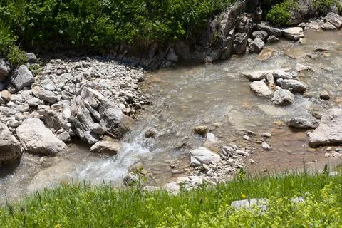 The source of the mountain river originates in the mountains on alpine meadow Stock Photos
