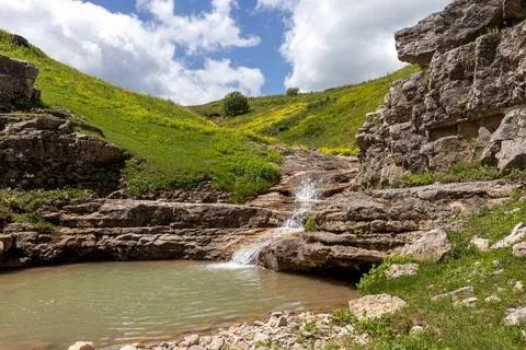The source of the mountain river originates in the mountains on alpine meadow Stock Photos