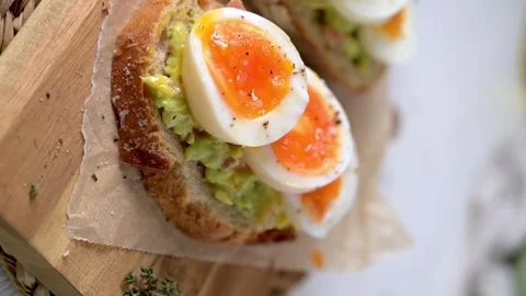Sourdough Toast Topped with Smashed Avocado and Soft Boiled Egg Slices Stock Footage 330689864