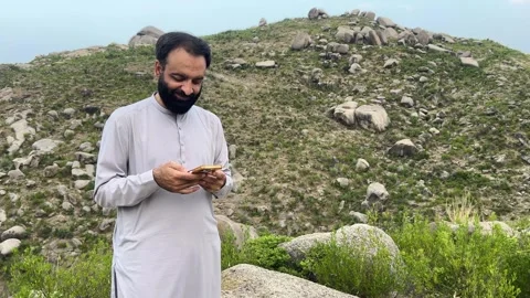 South Asian Man Reading Message on Smartphone in Mountain Landscape Stock Footage 344580941