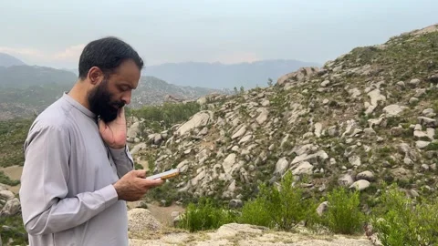South Asian Man Reading Mobile Message and Thinking in Mountain Landscape Stock Footage 344582453