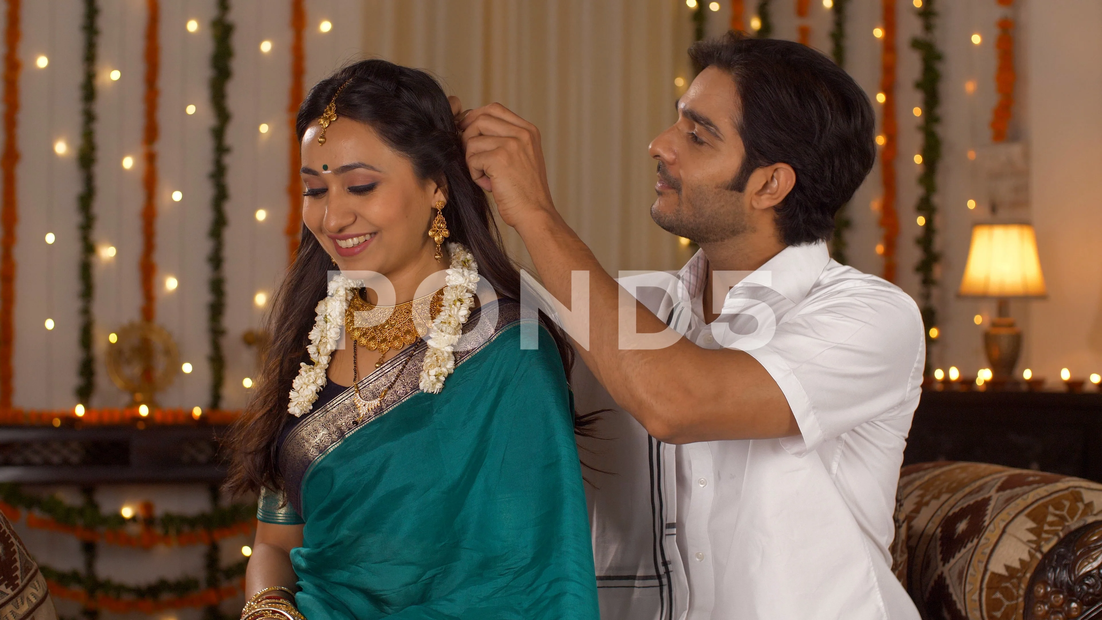 South Indian husband helping his pretty wife get ready for the festival